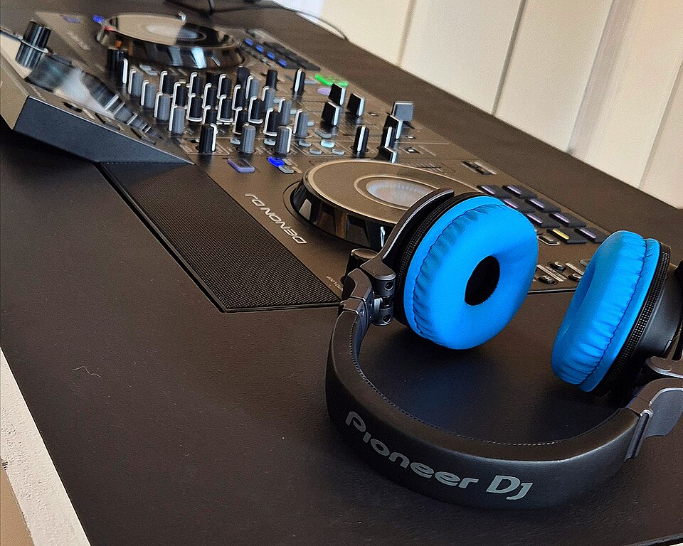Controlador DJ de dos decks con mixer central y auriculares.