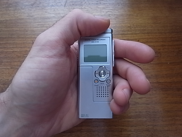 Grabador de voz compacto sostenido en una mano.